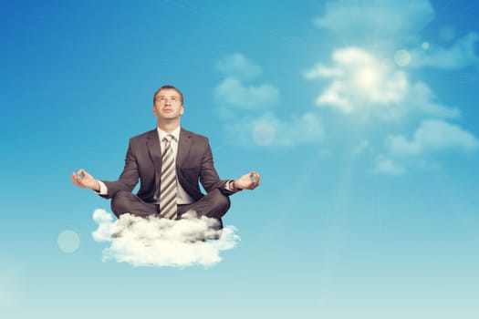 Businessman sitting in lotus position on cloud, looking up. Sky with sun as backdrop