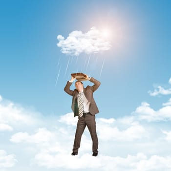 Businessman in suit standing on cloud and covered using briefcase from rain. Sky with sun as backdrop