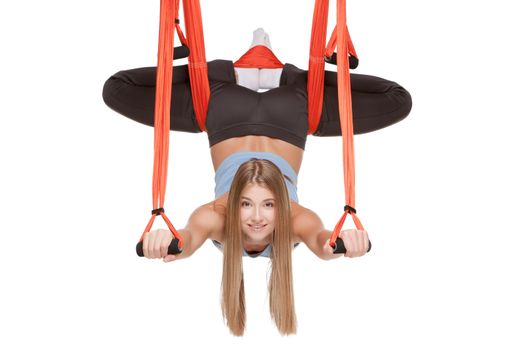 Young woman making antigravity yoga exercises with red hammock on a white background
