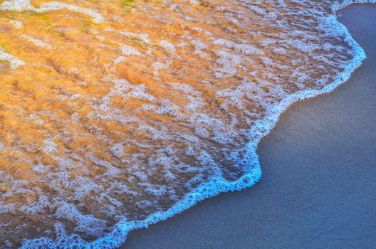 Transparent waves on the sandy beach