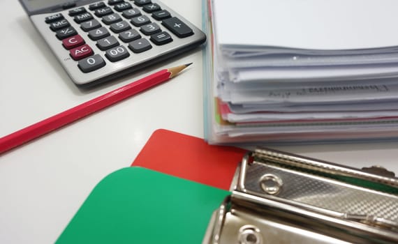 On the desk in the office, equipment to work including calculator, pencil, board and paper.                              