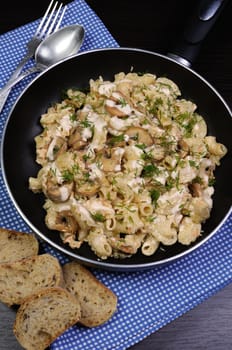 Pasta sauce with mushrooms in a pan on the table with bread and dill