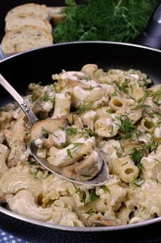 Pasta sauce with mushrooms in a pan on the table with bread and dill