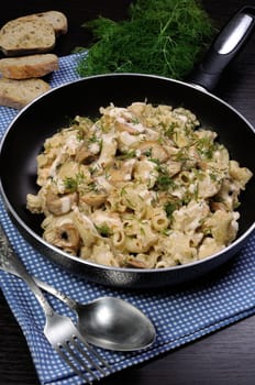 Pasta sauce with mushrooms in a pan on the table with bread and dill