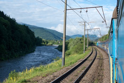 Passenger train going near the river in the Carpathian Mountains