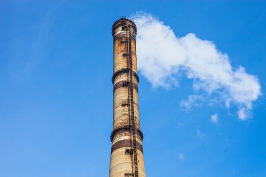 Smoke stack of the industrial plant against the blue sky