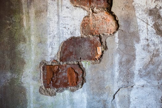 Bricks visible in the split plaster of the old wall.