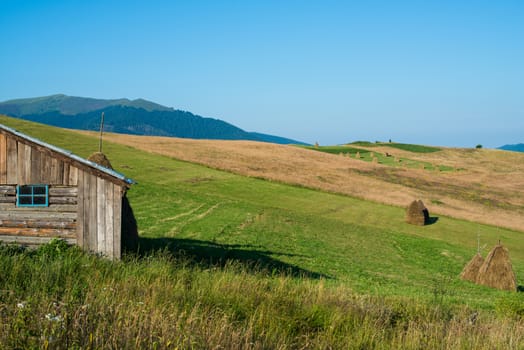 Summer landscape in the Ukrainian Carpathian Mountains with the wooden shed in the foreground,