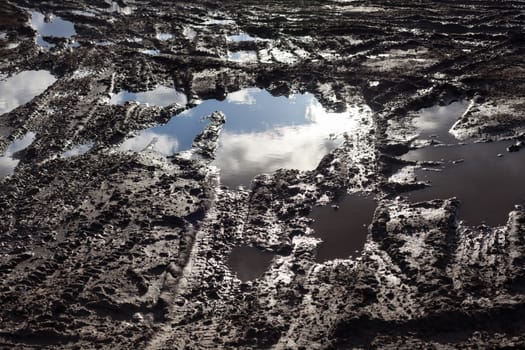 Mud and puddles on the dirt road.