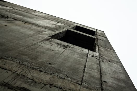 Concrete wall with window openings of the unfinished building against the white sky