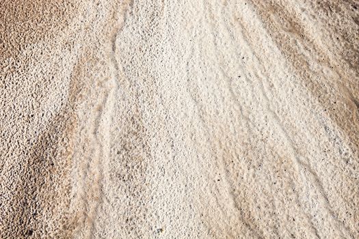 Sand surface after the rain with the visible traces of the raindrops and water currents