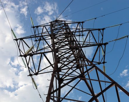 Electricity pylon against the cloudy sky background.