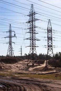 System of electricity pylons and power lines out-of-town near the dirt road,