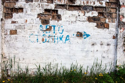 Old whitewashed brick wall with faded pointer in Cyrillic alphabet "Avtostoyanka" (parking) 