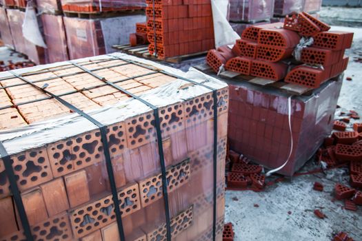 Stacks of silicate bricks on wooden pallets and in polyethylene