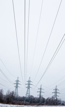 System of electricity pylons and power lines out-of-town in the winter day.