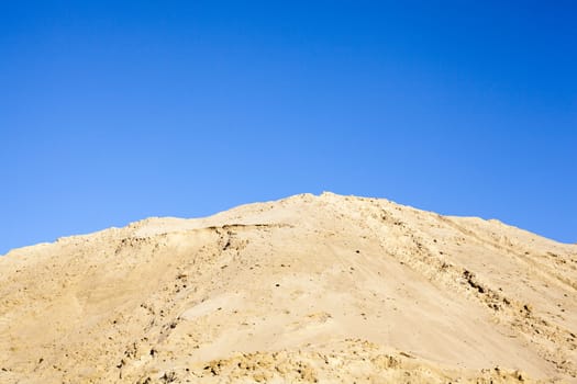 Pile of sand and clear blue sky over it.