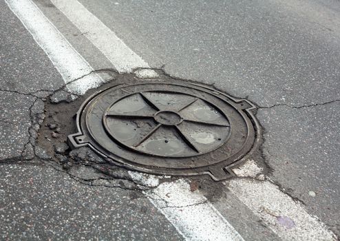 Manhole on the road within the double solid white center-lines of the road marking