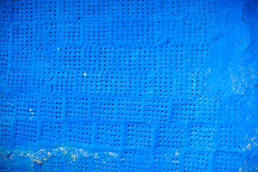 Blue painted surface with tiny holes and rich texture.
