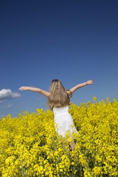 Young girl with Outstretched arms on a Rape Field