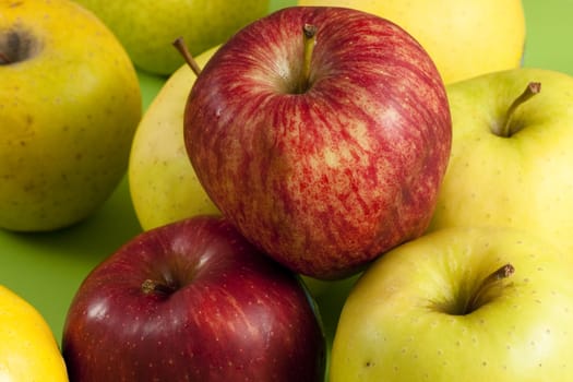 red and green apples on a green floor and a whole pear