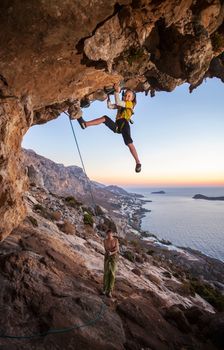 Seven-year old girl climbing a challenging route, father belaying. Kalymnos island, Greece
