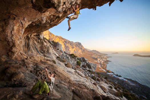 Seven-year old girl climbing a challenging route at sunset