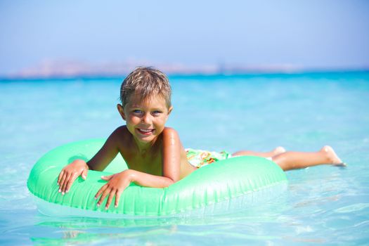 Happyboy playing on the inflatable rubber circle in the sea