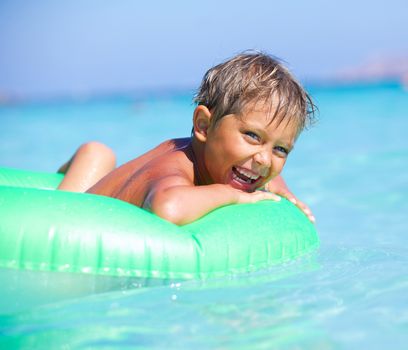 Happyboy playing on the inflatable rubber circle in the sea