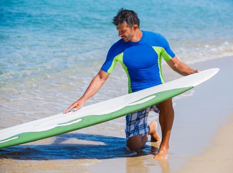 Strong young surf man at the beach with a surfboard.