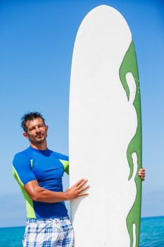 Portrait of strong young surf man at the beach with a surfboard.