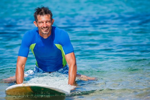 Strong young surf man at the beach with a surfboard.