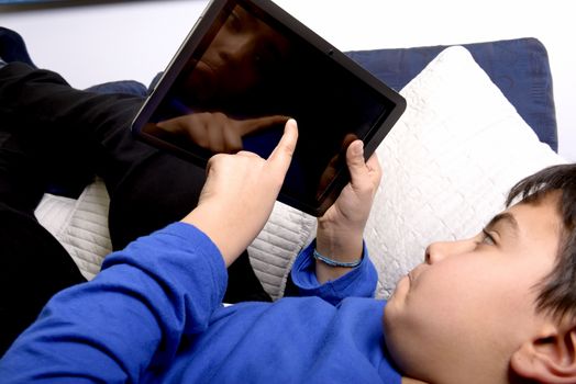 Child uses an iPad to communicate and play. Reflection of the face.