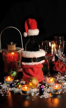 A bottle of wine at the Christmas table among candles, balls and glasses