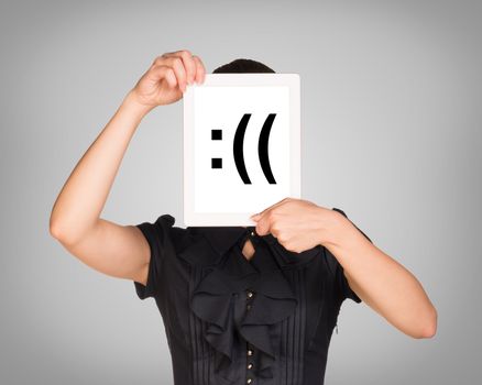 Woman in black dress covered her face with tablet. On screen code smiley. Gray background