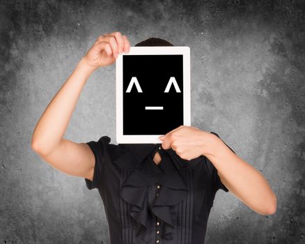 Woman in dress covered her face with tablet. On screen code smiley. Concrete background