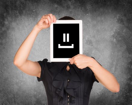 Woman in black dress covered her face with tablet. On screen code smiley. Concrete background