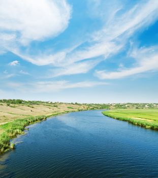 blue river and blue sky with clouds over it