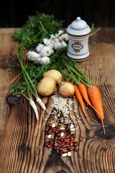 Beans, carrots, parsley, onions, potatoes and paprika on old traditional wooden board