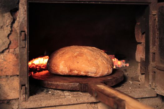 Bread baking in the old oven in the traditional way on carbon