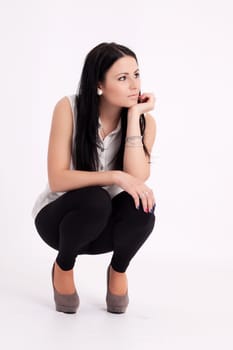 Young long-haired black-haired woman squatting thoughtful