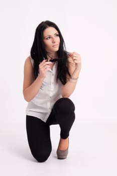 Young long-haired black-haired woman kneeling holding hair and thinking