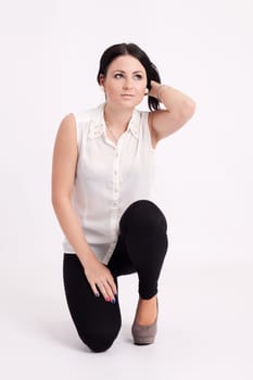 Young long-haired black-haired woman kneeling with hands in hair