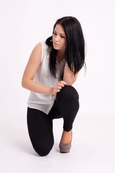 Young long-haired black-haired woman kneeling holding hair and thinking