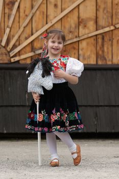 Smiling girl in traditional costume, holding a horse