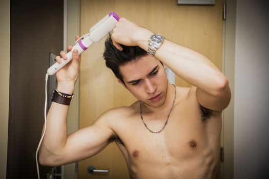 Shirtless Handsome Young Man Ironing his Short Hair in his Room While Looking Down