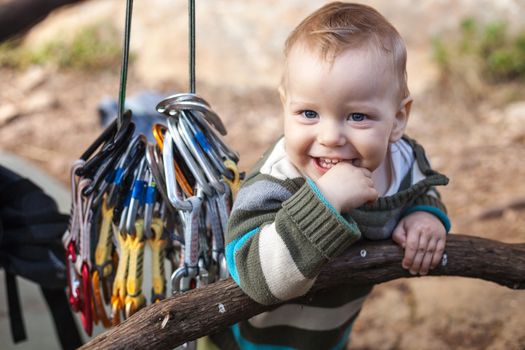 Child of rock climbers smiling while standing next to bundle of quickdraws