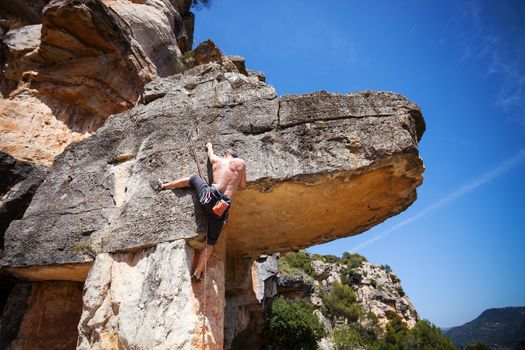 Male rock climber climbing on a cliff
