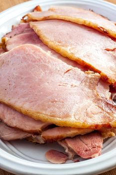 Fresh baked and slice ham on a white platter.