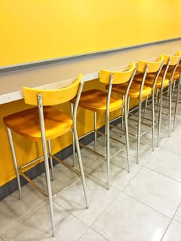 Bright cafeteria with a raw of yellow chairs.